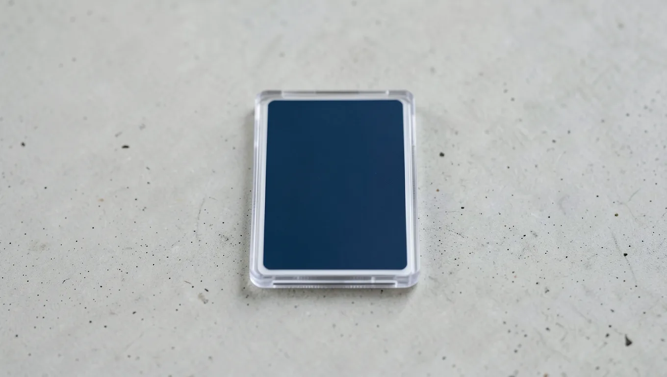 A trading card in a clear toploader on a light concrete surface